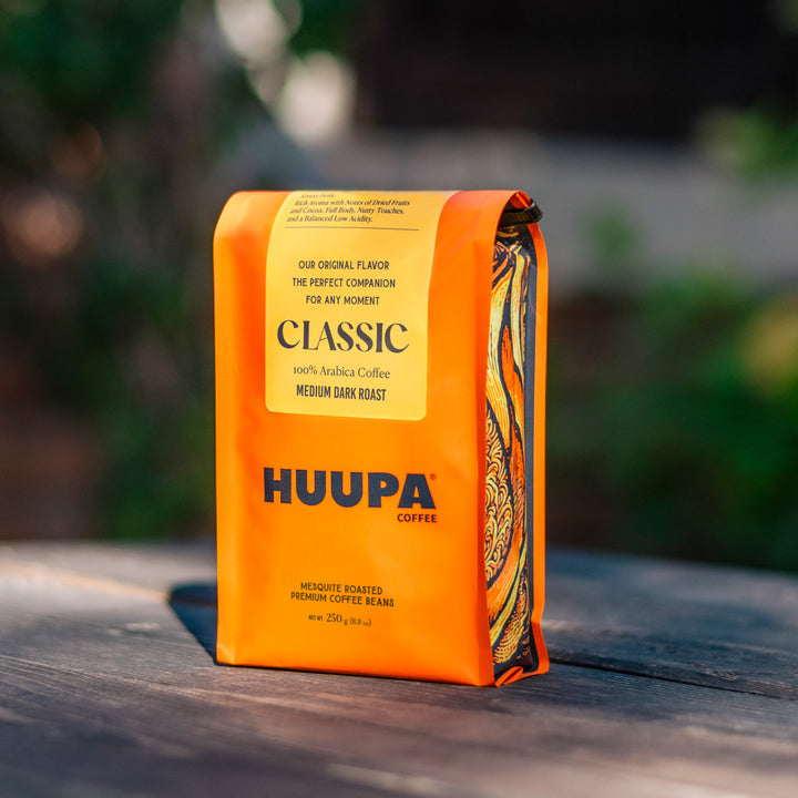Orange coffee bag with 'HUUPA' branding on a wooden surface with a blurred natural background