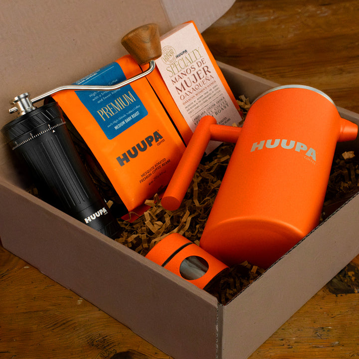 Orange HUUPA coffee grinder and packaging in a box on a wooden surface