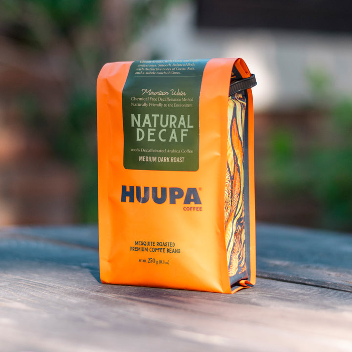 Orange Natural Decaf Huupa Coffee bag with green label on a wooden surface
