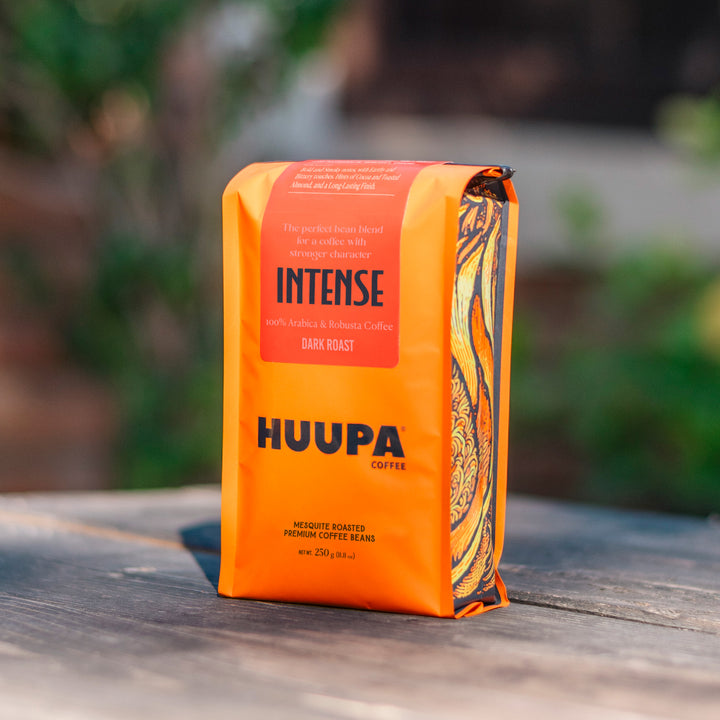 Orange coffee bag labeled 'HUUPA Coffee' with 'Intense' on a wooden surface.