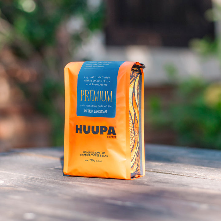 Orange coffee bag with blue label on a wooden surface outdoors