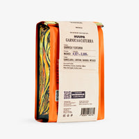 A package of Huupa Garnica & Caturra washed coffee, shown from the side. The packaging features a bright orange border, a cream-colored paper label with black text, and a colorful marbled pattern on the left side.